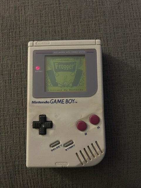 Rear of gray Nintendo Game Boy with battery cover and Nintendo service sticker