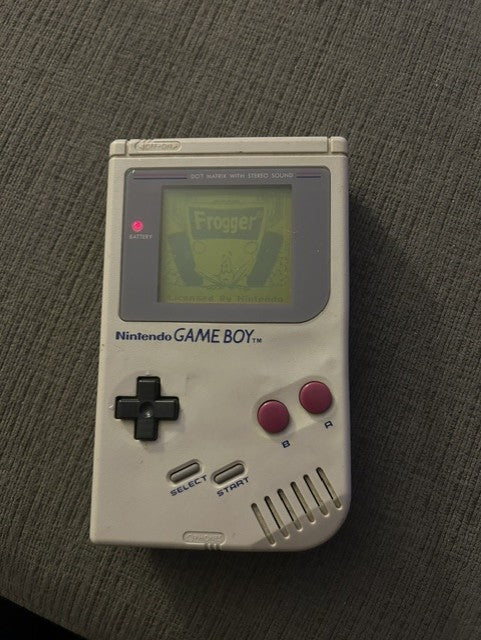 Rear of classic gray Nintendo Game Boy Unit C with worn barcode sticker and battery cover