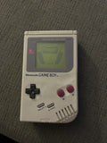 Rear of classic gray Nintendo Game Boy Unit C with worn barcode sticker and battery cover